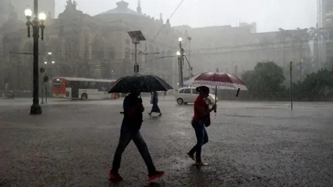 Pessoas caminham durante tempestade no centro de São Paulo